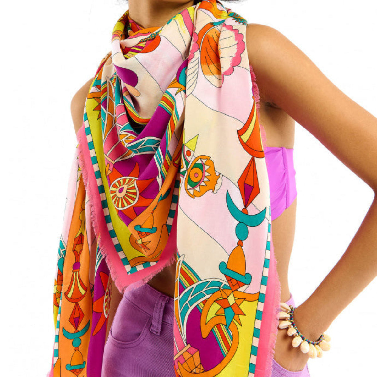 Baigné dans un univers fantasmagorique et hallucinogène, ENCHANTERED se pare en son centre d'un œil façon pentacle autour duquel quatre soleils aux visages poupons viennent se dessiner. Dans cette même veine, le reste du foulard raconte un monde à part, à la frontière de l'inconscient et d'un imaginaire débridé et coloré, sur fond de larges rayures empruntées à l'esthétique des années 70. Décliné en deux couleurs, ENCHANTERED est ici dans sa version rose et se révèle dans des tons turquoise, jaunes, oranges