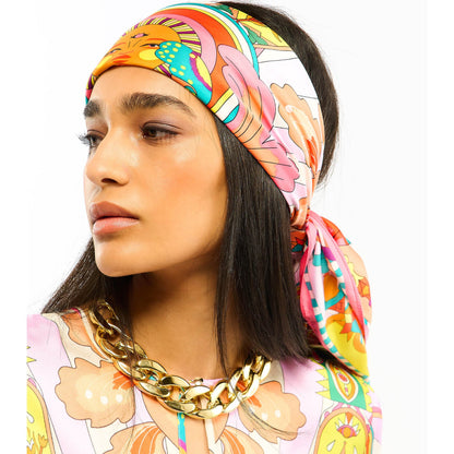 Baigné dans un univers fantasmagorique et hallucinogène, ENCHANTERED se pare en son centre d'un œil façon pentacle autour duquel quatre soleils aux visages poupons viennent se dessiner. Dans cette même veine, le reste du foulard raconte un monde à part, à la frontière de l'inconscient et d'un imaginaire débridé et coloré, sur fond de larges rayures empruntées à l'esthétique des années 70. Décliné en deux couleurs, ENCHANTERED est ici dans sa version rose et se révèle dans des tons turquoise, jaunes, oranges