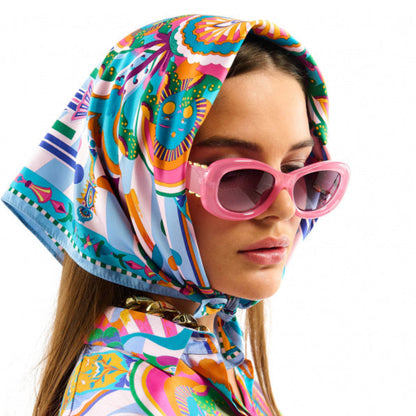 Baigné dans un univers fantasmagorique et hallucinogène, ENCHANTERED se pare en son centre d'un œil façon pentacle autour duquel quatre soleils aux visages poupons viennent se dessiner. Dans cette même veine, le reste du foulard raconte un monde à part, à la frontière de l'inconscient et d'un imaginaire débridé et coloré, sur fond de larges rayures empruntées à l'esthétique des années 70. Décliné en deux couleurs, ENCHANTERED est ici dans sa version bleue et se révèle dans des tons orange corail, rose 