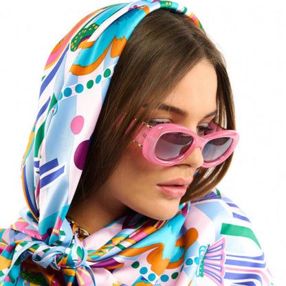 Baigné dans un univers fantasmagorique et hallucinogène, ENCHANTERED se pare en son centre d'un œil façon pentacle autour duquel quatre soleils aux visages poupons viennent se dessiner. Dans cette même veine, le reste du foulard raconte un monde à part, à la frontière de l'inconscient et d'un imaginaire débridé et coloré, sur fond de larges rayures empruntées à l'esthétique des années 70. Décliné en deux couleurs, ENCHANTERED est ici dans sa version bleue et se révèle dans des tons orange corail, rose fuchs